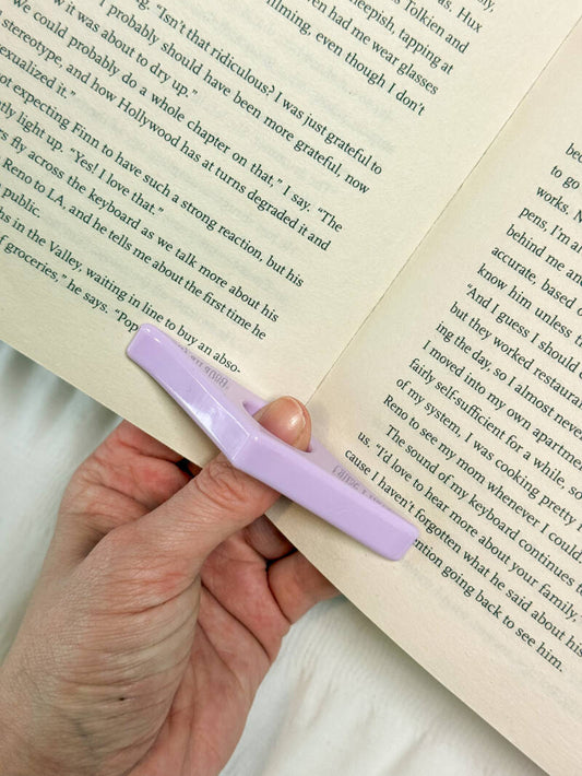 Lila duimring leeshulp van Charms of Chapters, perfect om moeiteloos een boek open te houden tijdens het lezen.