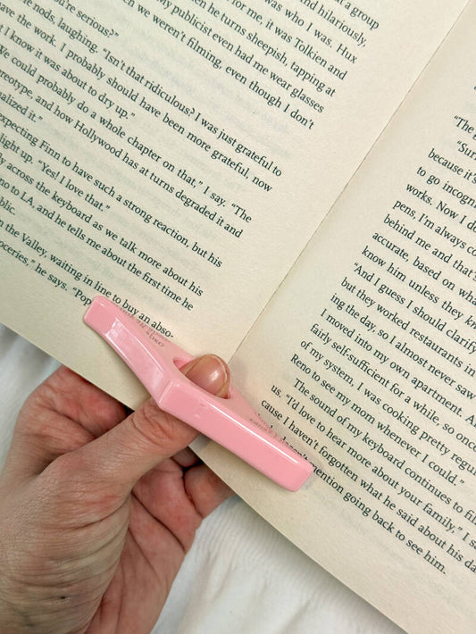 Roze duimring leeshulp van Charms of Chapters, perfect voor handsfree lezen zonder de pagina’s dicht te laten vallen.