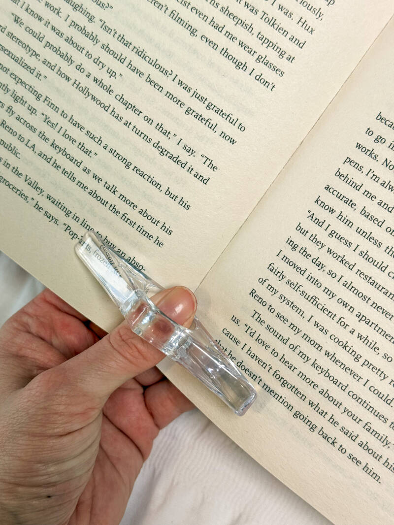 Transparante duimring leeshulp van Charms of Chapters, perfect om boeken open te houden zonder moeite.