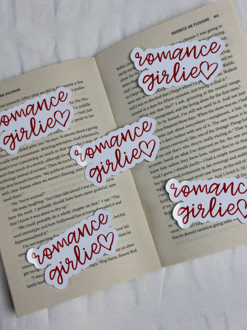 Sticker met de quote 'Romance Girlie' in sierlijke rode handgeschreven letters, inclusief een hartje, ideaal voor romance lezers.