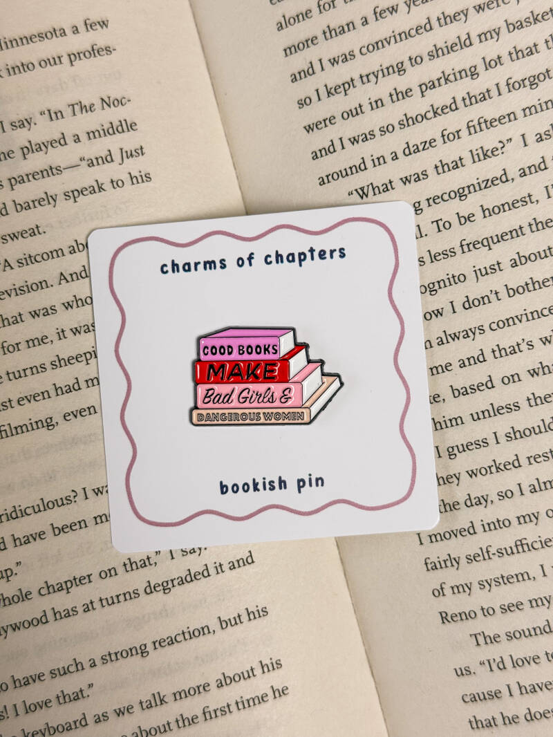 Enamel pin met een stapel roze en rode boeken en de tekst: 'Good Books Make Bad Girls & Dangerous Women', perfect voor boekenliefhebbers.