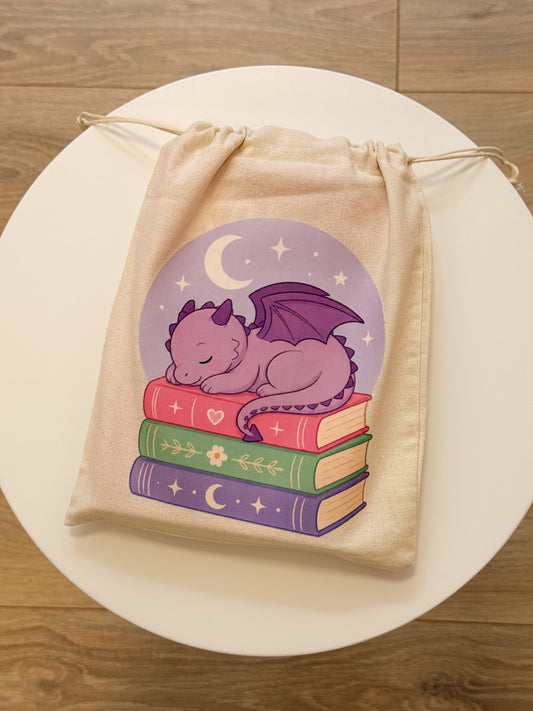 Book pouch Sleeping Dragon met slapend draakje op een stapel boeken.